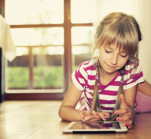 stock photo of young girl laying on floor using a tablet