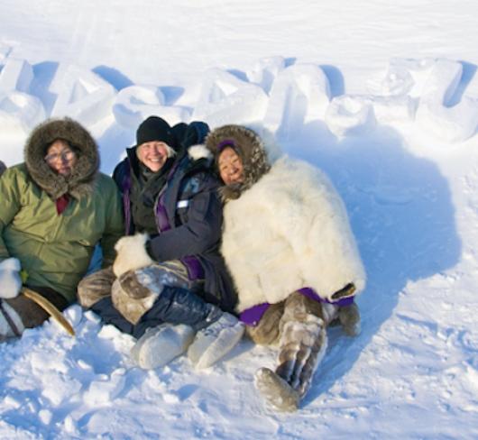 aboriginal women wearing parkas sitting in the snow