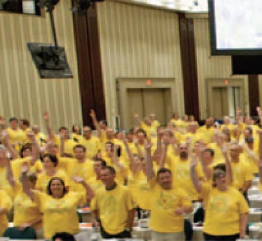 crowd of ETFO members wearing yellow shirts with hands in the air