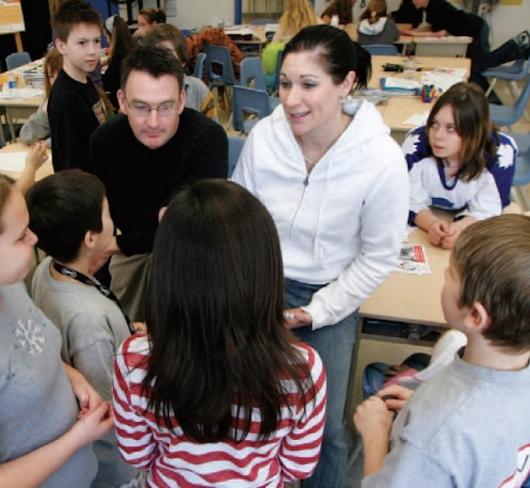 Teacher standing with students providing an explenation 