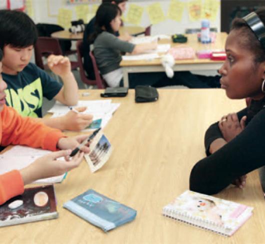 two students sitting at desk with teacher