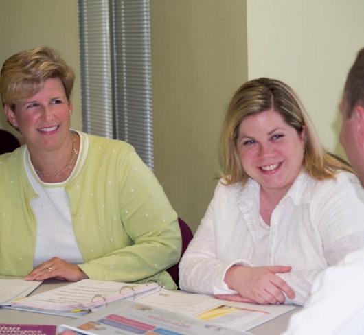 Teachers sitting together smiling at one another
