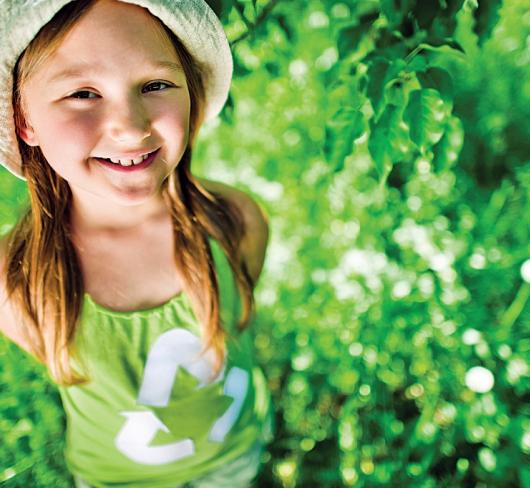 Young girl wearing green recycle shirt in field of grass