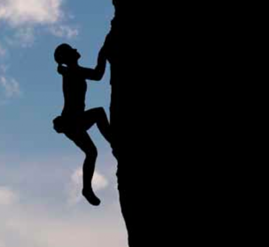 Silhouette of woman climbing cliff