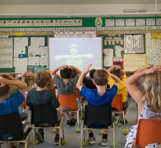 Young students facing projection with hands on heads