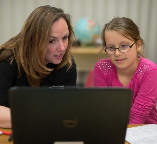 Teacher working with student using a laptop