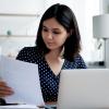 Woman sitting at laptop examining document